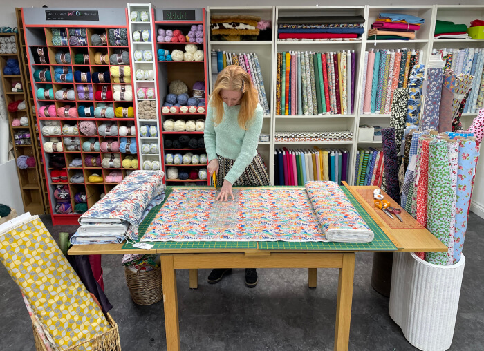 suzanne kelly measures fabric at stitch