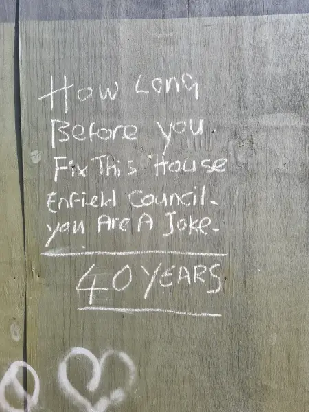 graffiti on hoarding around broomfield house reading how long before you fix this house enfield council 1