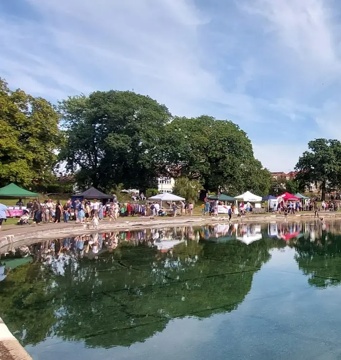 stalls at palmers green festival 2023 next to boating pond filled with water