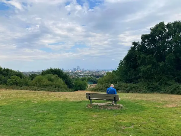 person on a bench with view over london from parliament hill