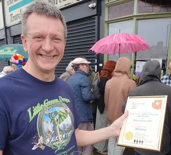 richard reeve outside little green dragon with pub of the year certificate